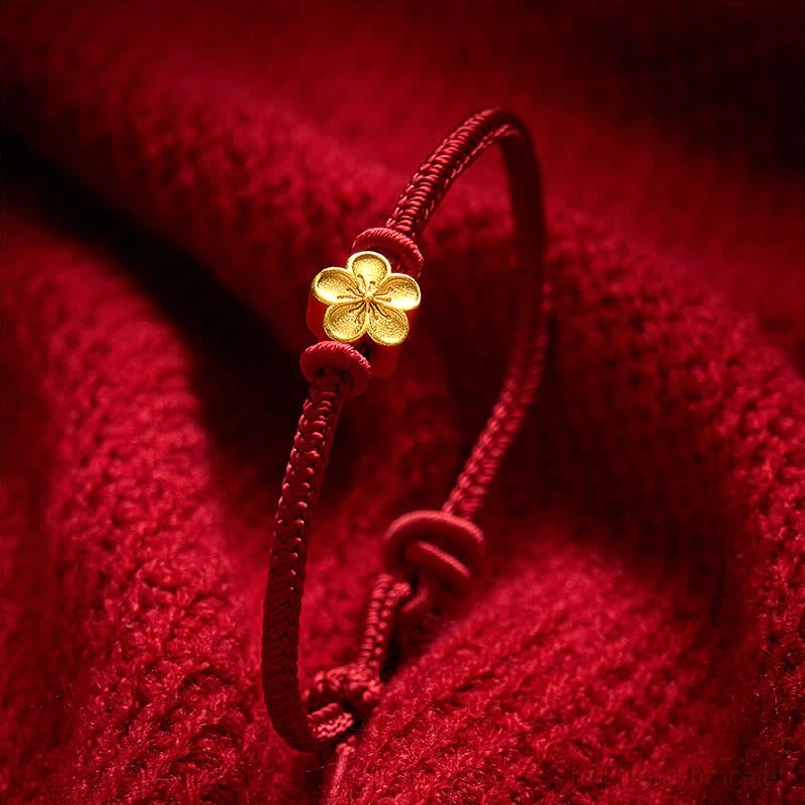 Close-up detail of red braided cord and adjustable gold peach blossom charm