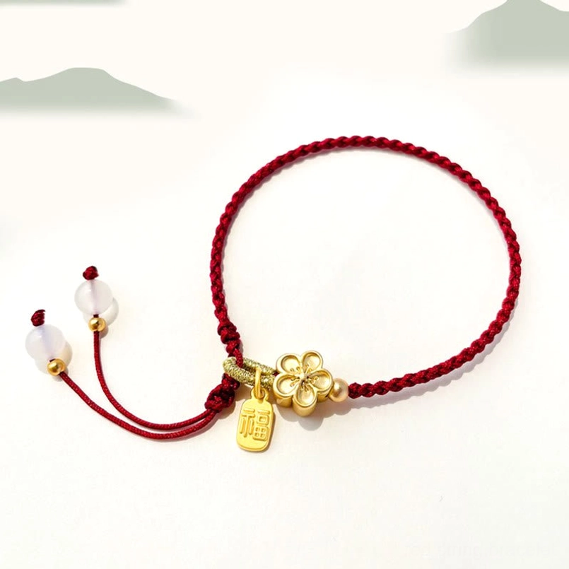 Red string lucky bracelet with peach blossom charm, Fu pendant, and adjustable bead tassel on white background