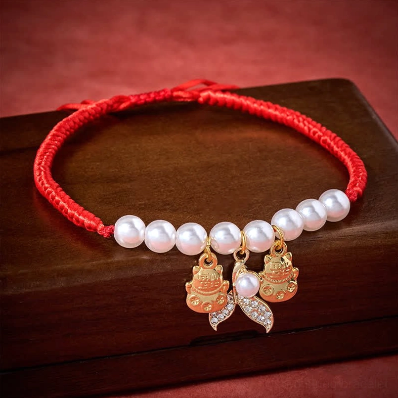 Red woven pet collar with lustrous white pearls and diamond-studded fish tail lucky cat charms detail view