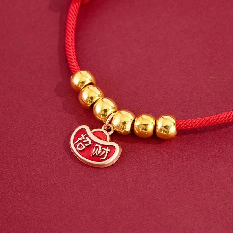Close-up macro view of red string pet collar with large yuanbao ingot pendant and gold barrel beads