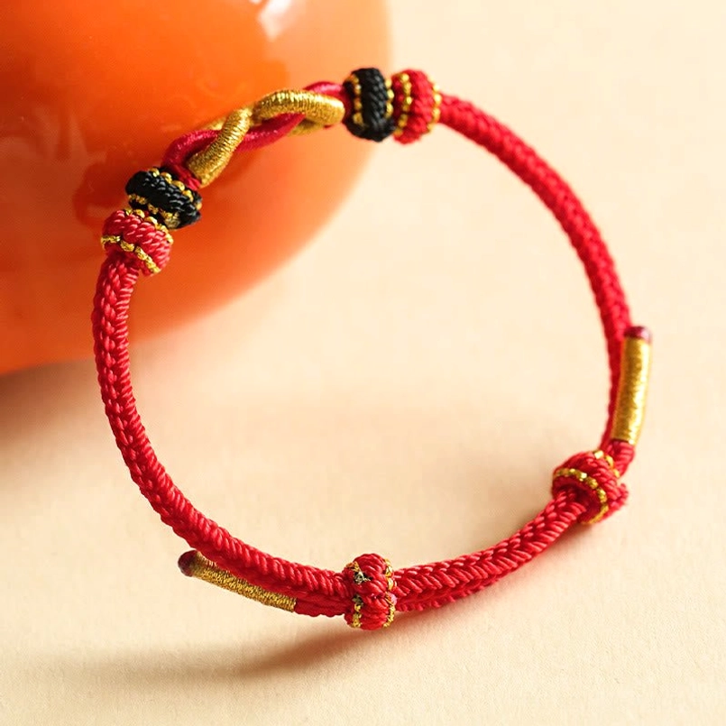 Close Up Red Rope Ingot Bracelet On Orange Ceramic Prop