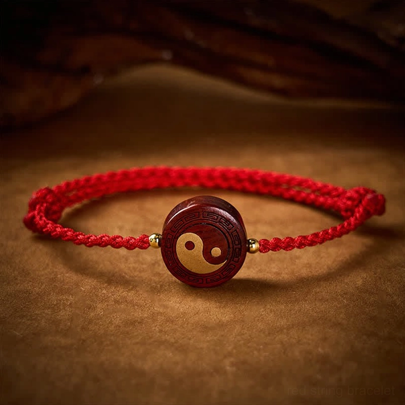 Handcrafted wooden yin yang charm with braided red rope and gold accent beads, eye-level perspective