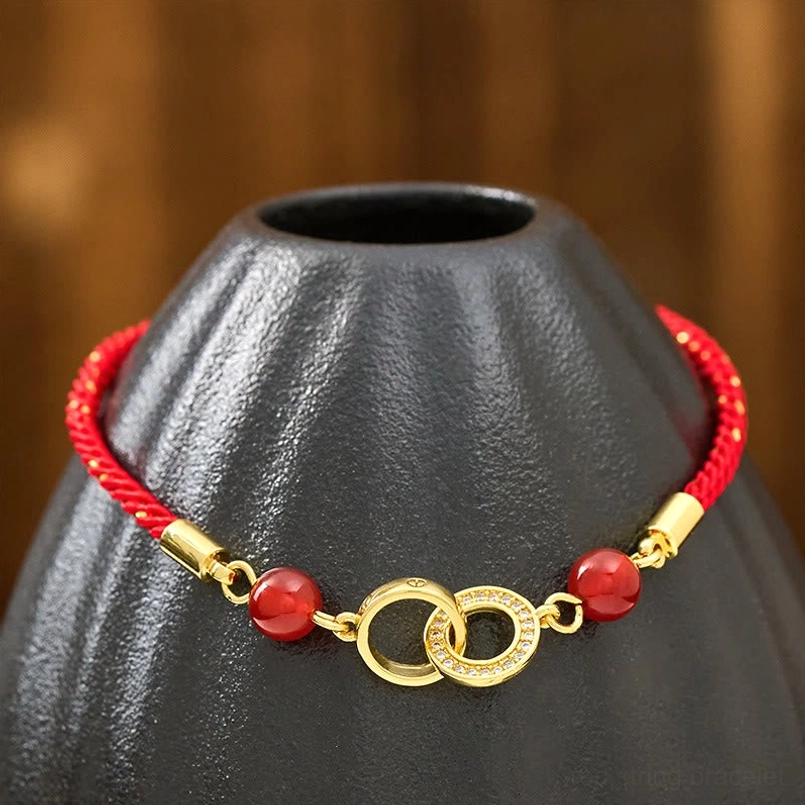 Front flat lay of red string protection bracelet with double gold rings on ceramic stand