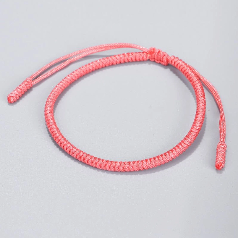 Light pink Tibetan protection bracelet smooth twisted cord dual adjustable tassels gray background
