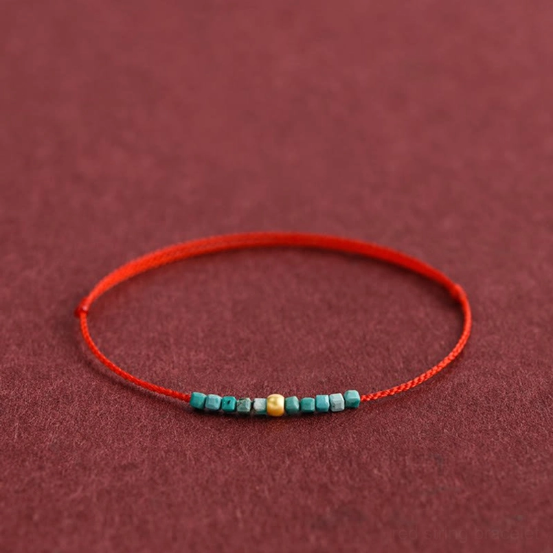 Turquoise gold beaded red braided bracelet side view on wine fabric background