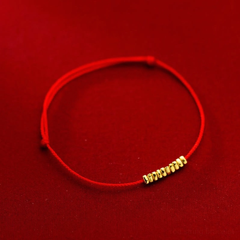 Handmade red cord bracelet with sterling silver charms on red velvet background