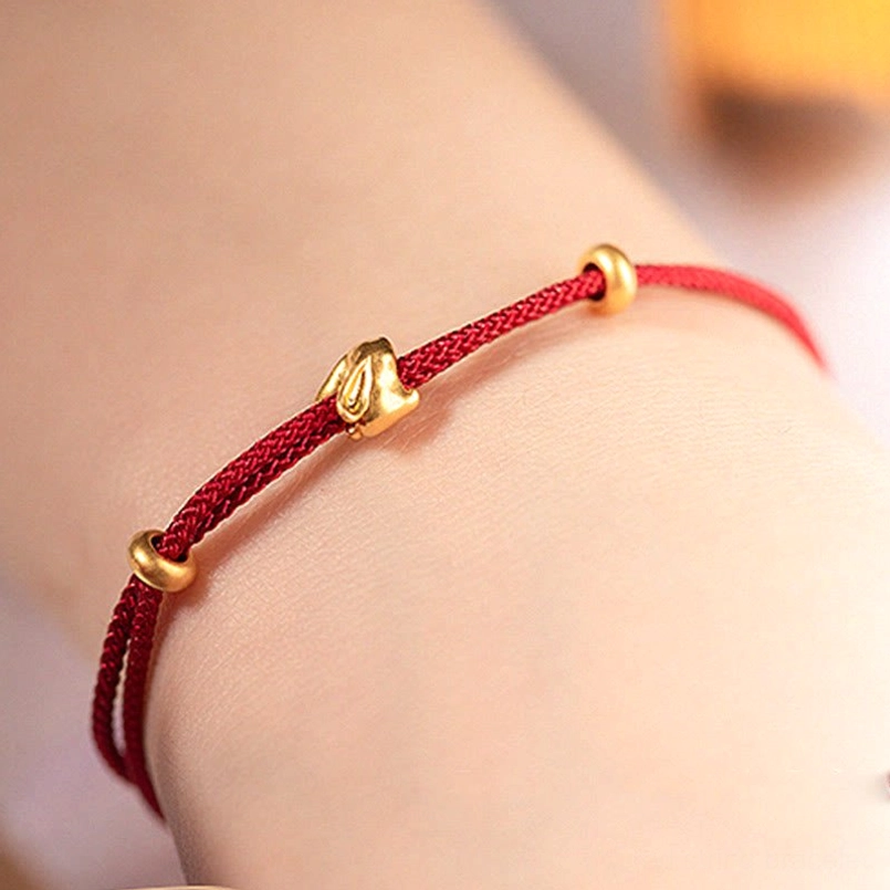 gold lucky rabbit red string bracelet worn on wrist close up view