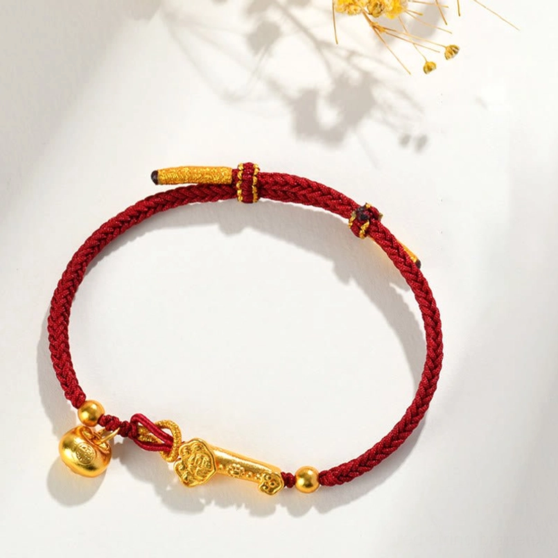 Adjustable red string lucky bracelet with sliding knot closure and gold charms flat lay