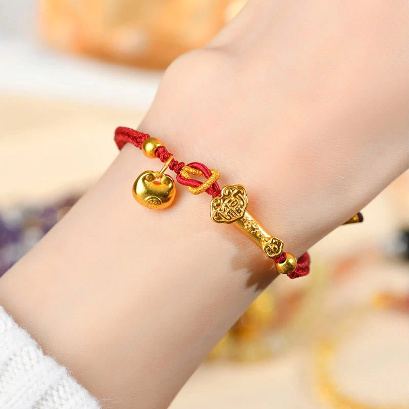 Close-up of red lucky bracelet on wrist with Ruyi and bell metal charms