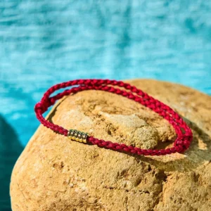 Dark red sterling silver bead bracelet overhead flat lay on yellow stone with blue backdrop