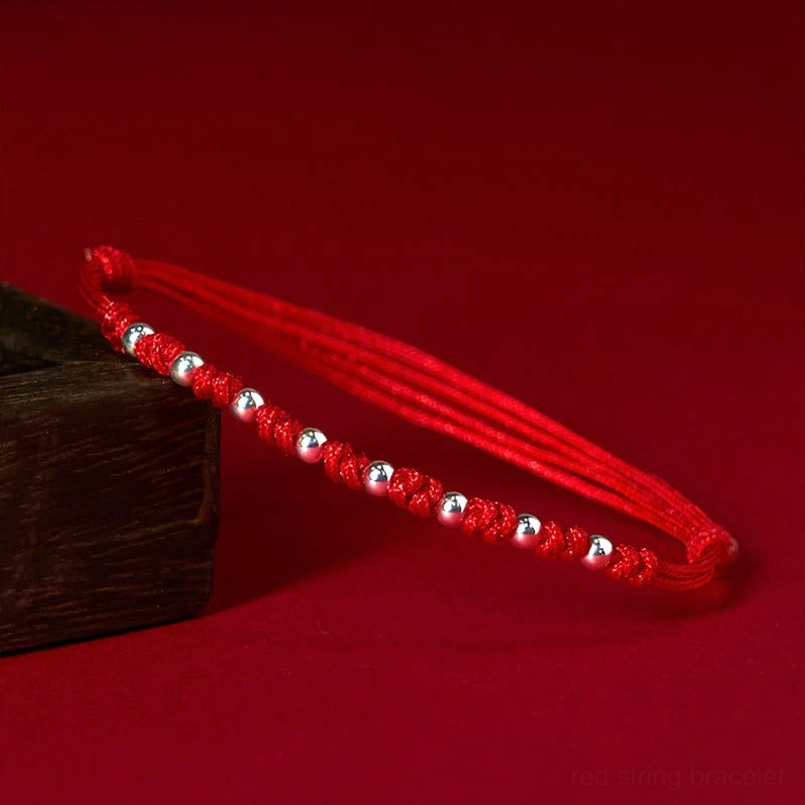 925 sterling silver red string bracelet with adjustable knots side view on wooden surface