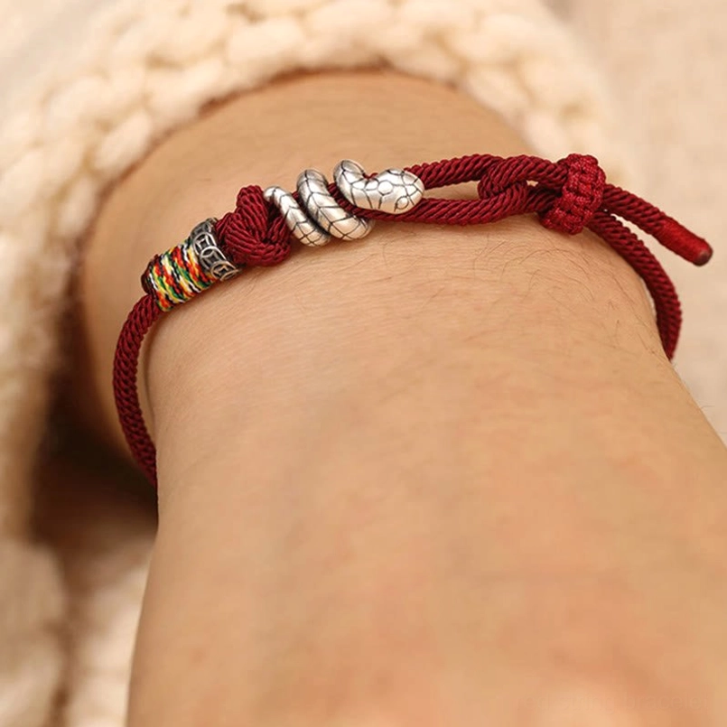 Red string snake bracelet worn on wrist with adjustable pull knot, wearable close-up