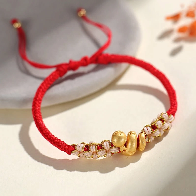 Red string snake charm bracelet side view on gray ceramic plate