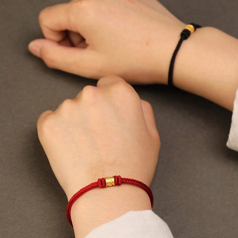 Red string Tibetan luck protection bracelet side view dark grey background