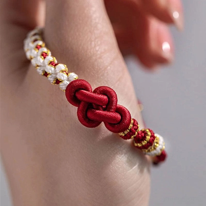 Red string true love knot bracelet held in hand showing delicate woven design and gold accents