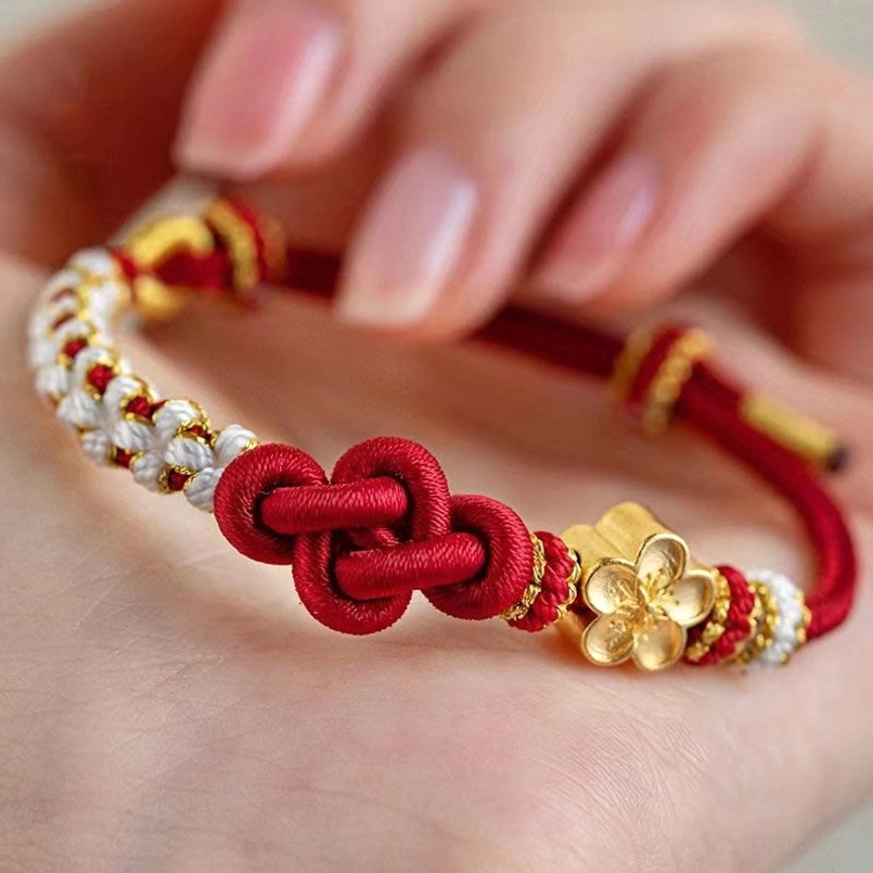 Handmade red string true love knot bracelet with gold peach blossom charm and white beaded accents close-up