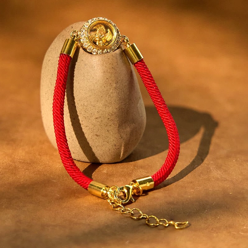 Close-up side view of red string feng shui bracelet revealing carved pattern inside rotating charm