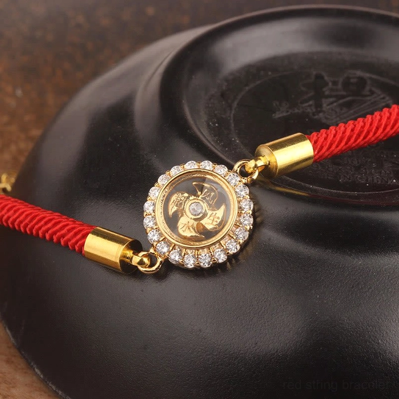 Red string feng shui windmill bracelet detail shot highlighting rotating copper charm and braided cord construction