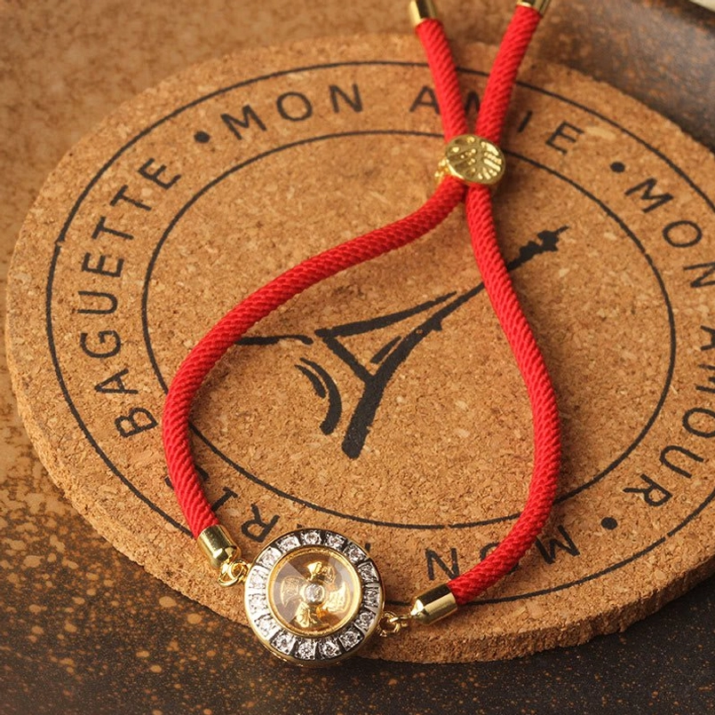 Red string braided bracelet with gold decorative bead and sparkling rotating charm