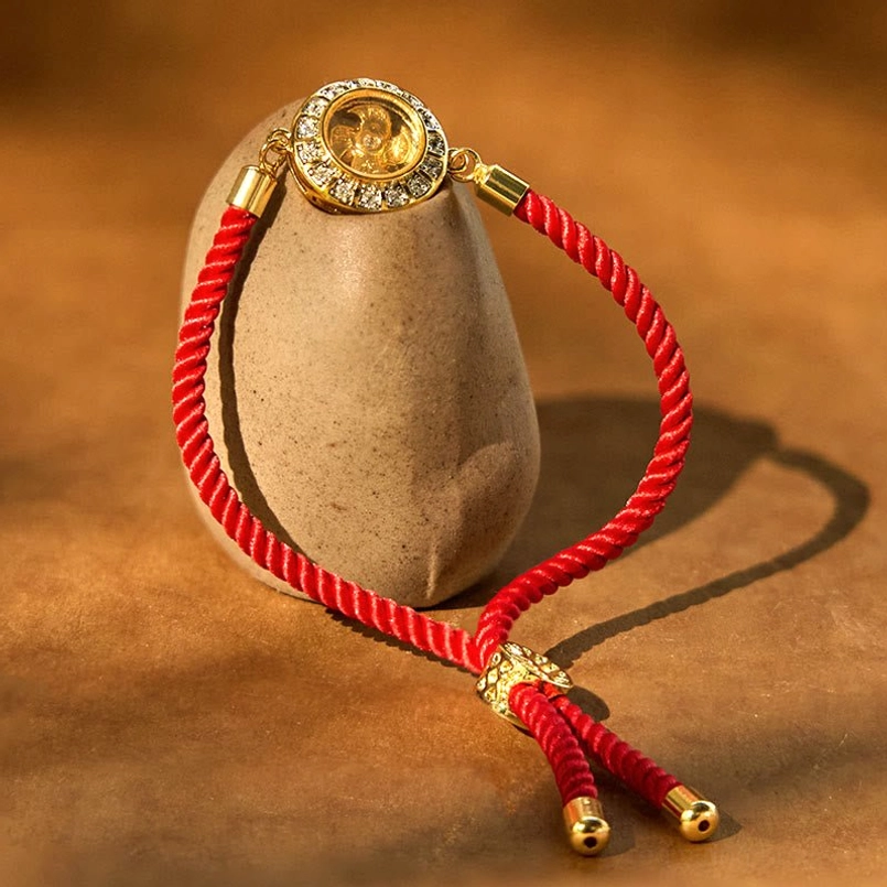 Red string faith bracelet with adjustable knot and rotating gold windmill charm on stone