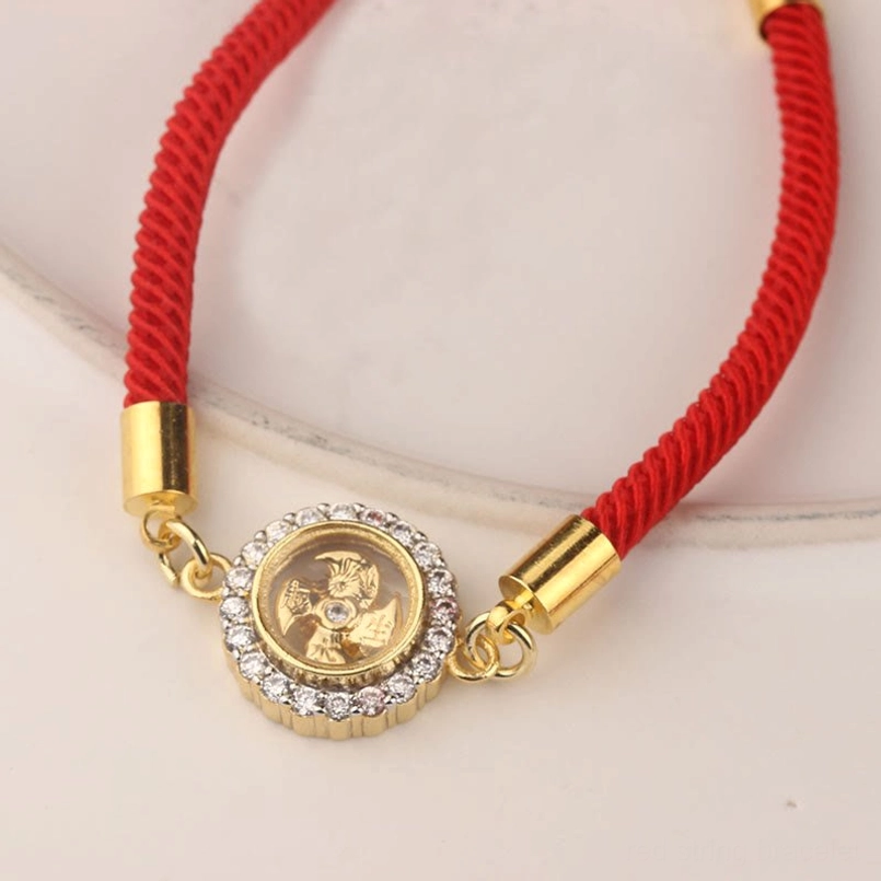 Side view of red braided string feng shui bracelet with rotatable copper windmill charm and crystal setting