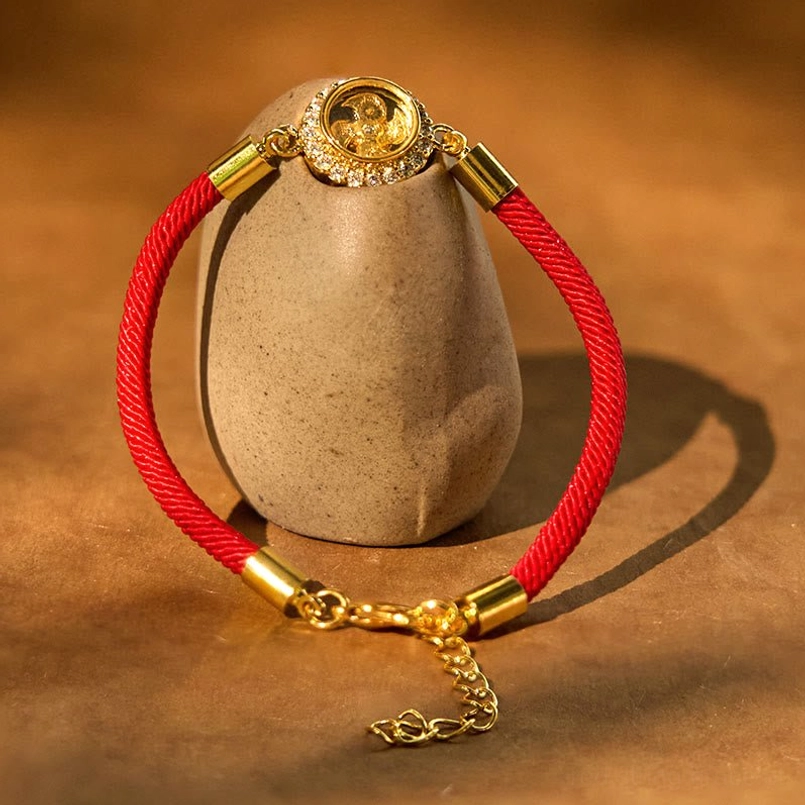 Red string feng shui bracelet side view showing adjustable extension chain and rotating copper centerpiece