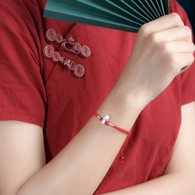 Red string bracelet side view worn on wrist with Chinese traditional outfit styling