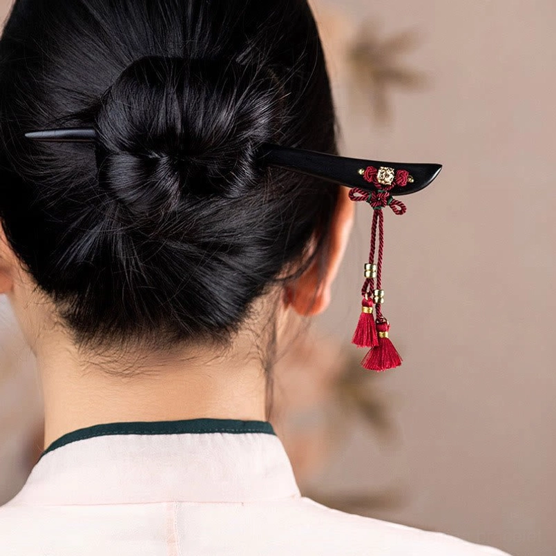 Red tassel hairpin worn in hair bun back view traditional styling