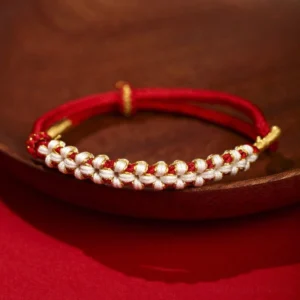 Red Tibetan peach blossom knot red string bracelet with gold accents on wooden plate