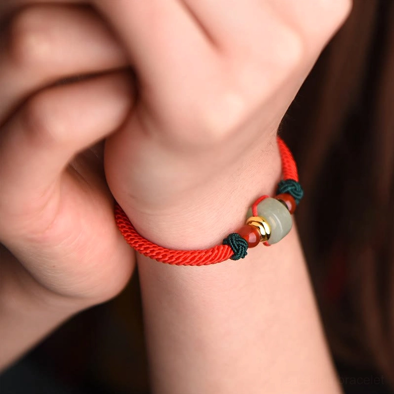Single red braided string bracelet with green aventurine barrel bead and red agate beads, wrist flat lay
