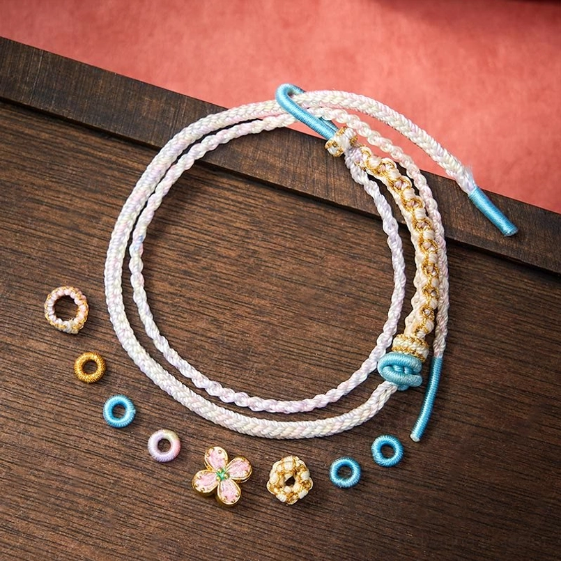 Red woven bracelet with peach blossom charm wooden background display