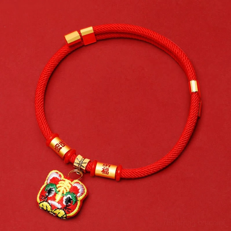 Red woven pet collar with gold-toned tiger head pendant overhead view