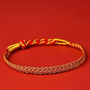 Red and yellow handwoven luck bracelet flat lay, adjustable knotted design on solid red background