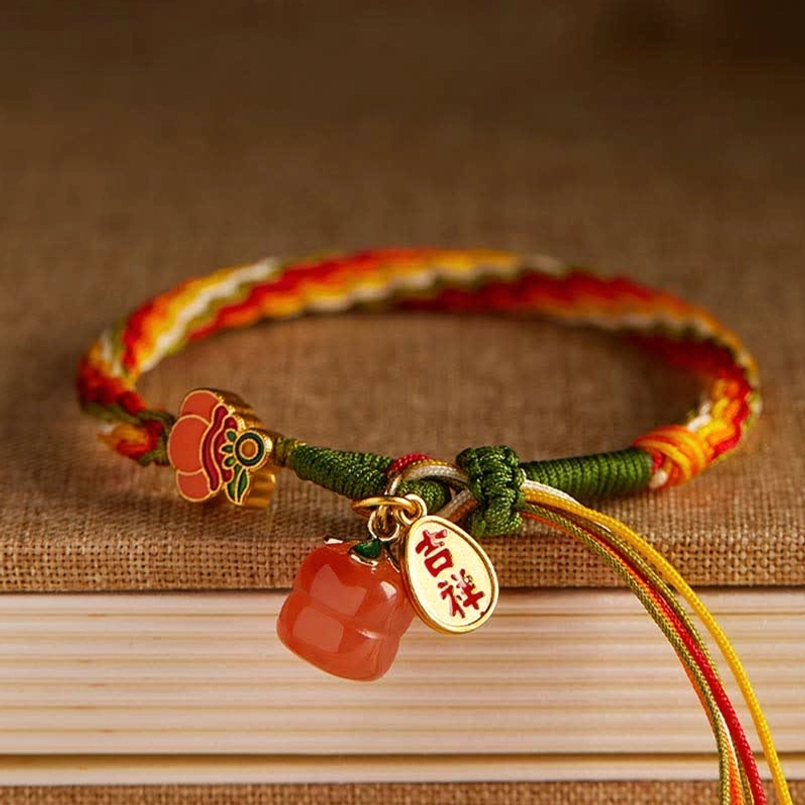Reincarnation knot bracelet with auspicious metal tag and enamel flower charm on vintage book