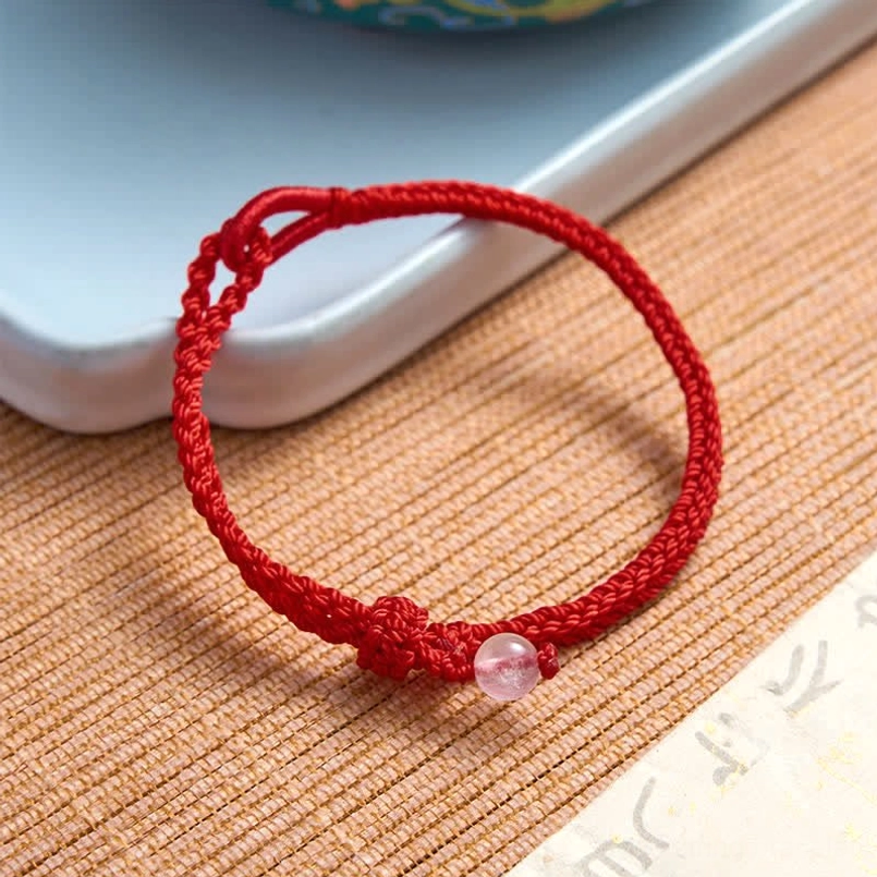 Rose quartz red string bracelet with fixed knot detail on printed calligraphy paper