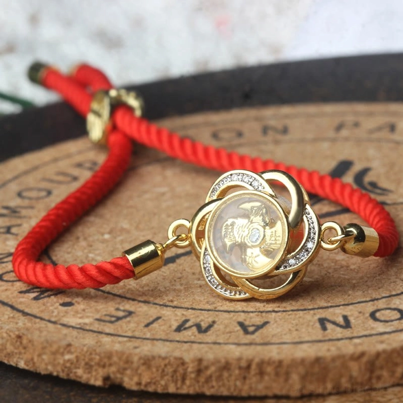 Rotatable plum windmill red string bracelet placed on engraved wooden coaster