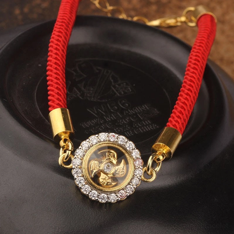 Close-up feng shui red string bracelet with engraved rotatable windmill charm and diamond-halo CZ stones on black display