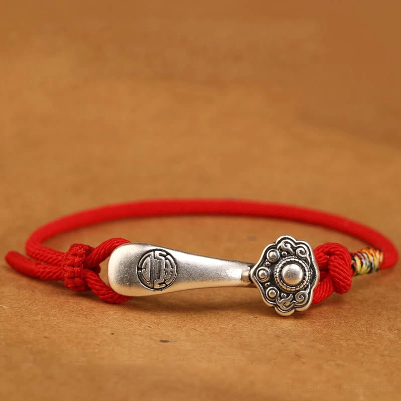 Bright red Ruyi stick woven bracelet with vintage silver pendant - overhead close-up showing vibrant red cord and detailed charm