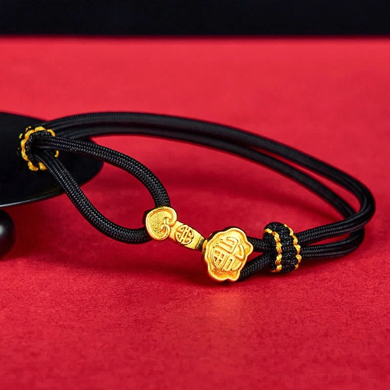 Black rope bracelet with gold Ruyi Fu character charms, adjustable woven design on red background