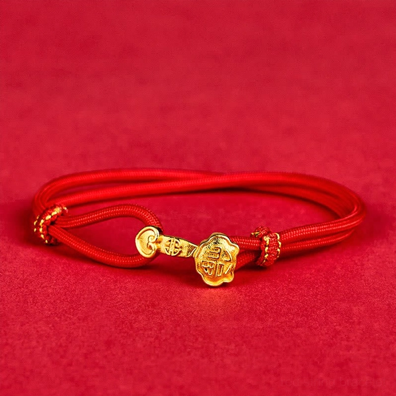 Top-down view of red rope bracelet with copper-plated gold Ruyi Fu character charm centered