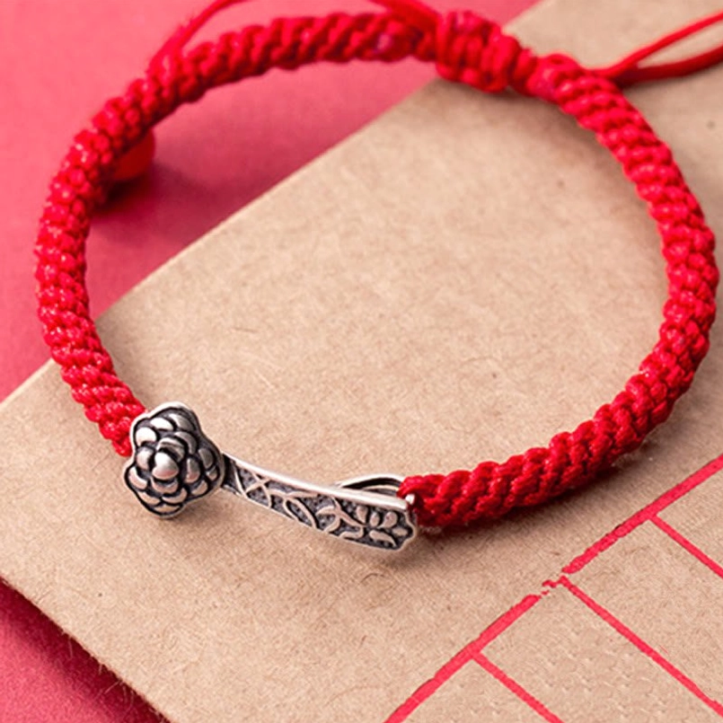 Complete Ruyi red string bracelet full display with 925 silver charm and red agate bead on beige paper with red grid
