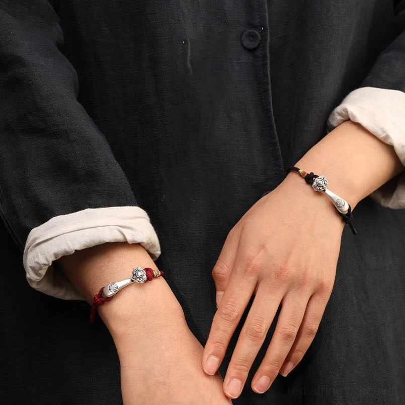 Two people wearing Ruyi protection bracelets - wrist close-up showing red cord and thin silver bracelet variants with silver charms