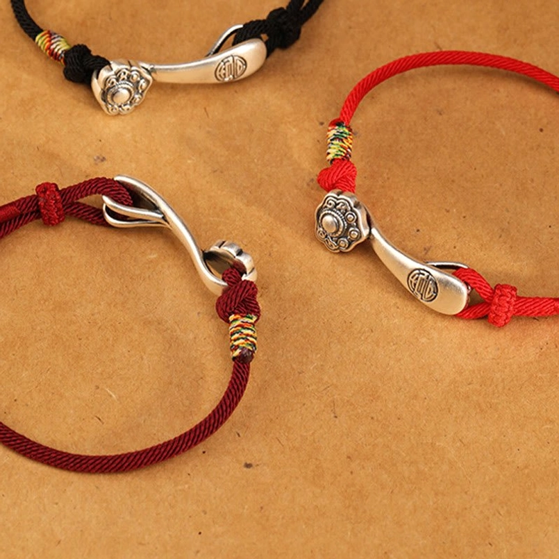 Red string Ruyi protection bracelet product shot - displaying complete design with silver charm, knots, and braided rope in natural lighting