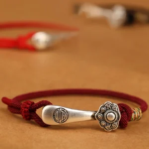 999 sterling silver Ruyi stick protection bracelet with wine red cord - overhead close-up view showing intricate braiding and detailed silver charm