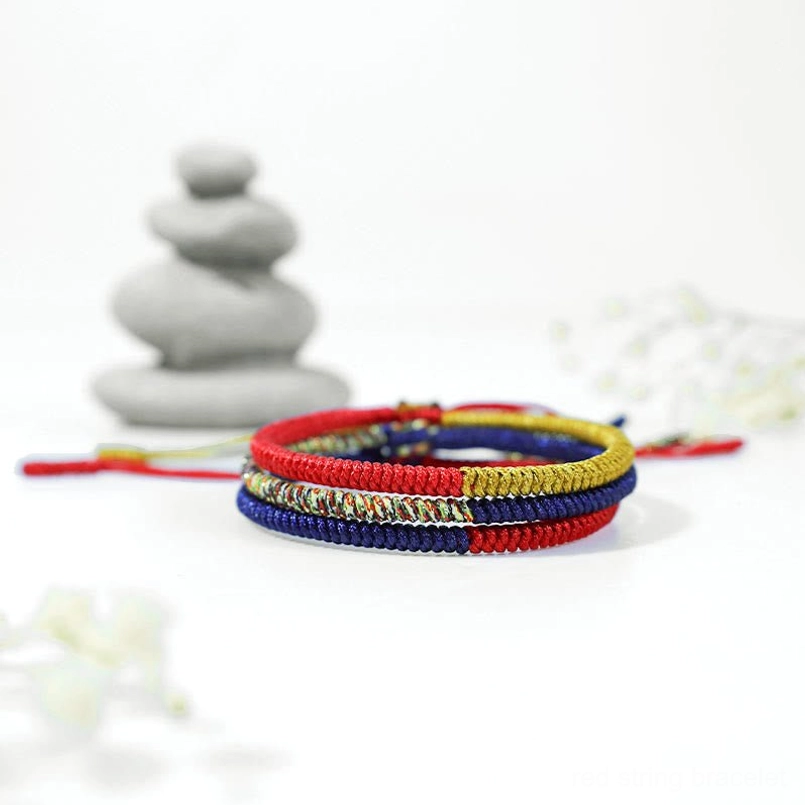 Tibetan woven red string bracelet on zen decor background
