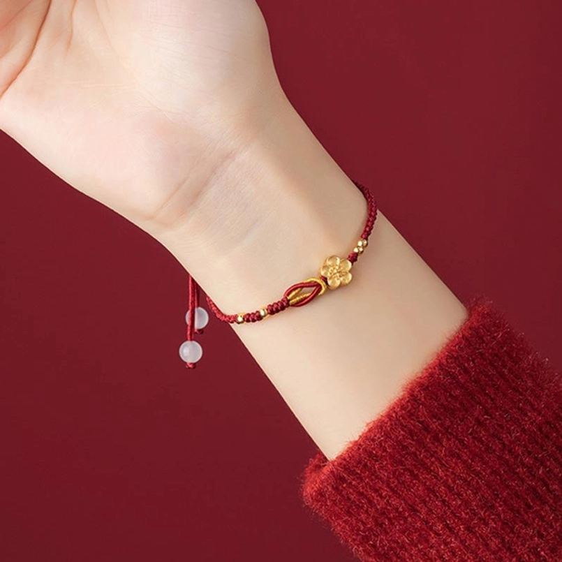Sakura red string bracelet side wrist close-up on wearer red knit sweater backdrop