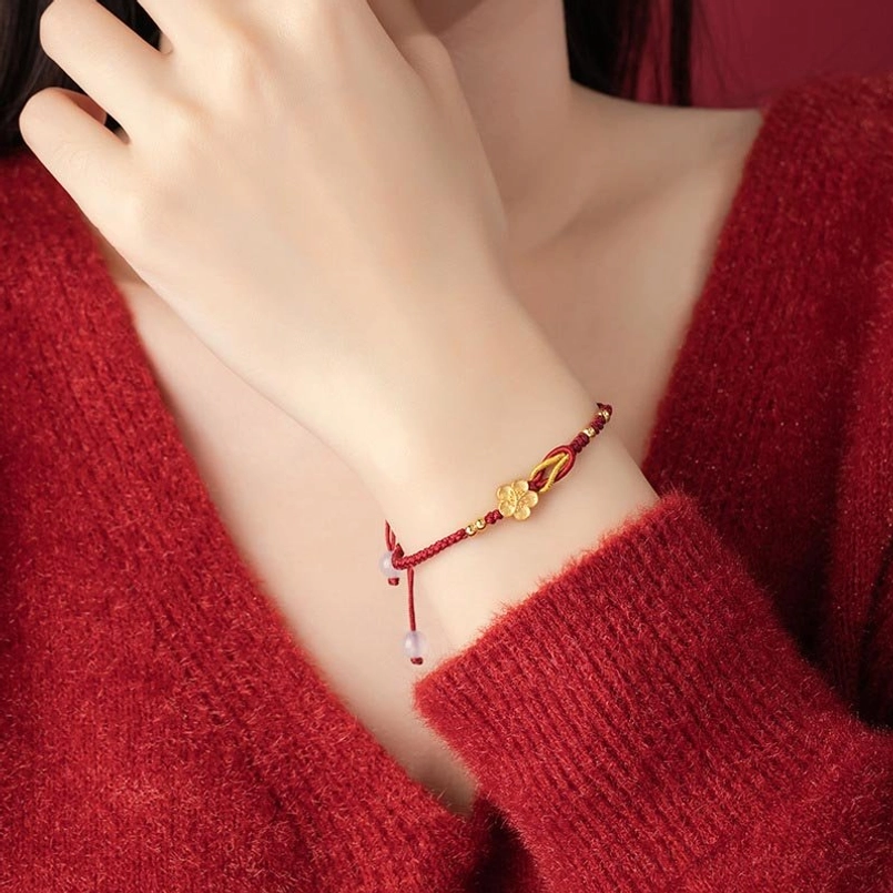 Sakura red string bracelet close-up on wearer wrist with red knit sweater background