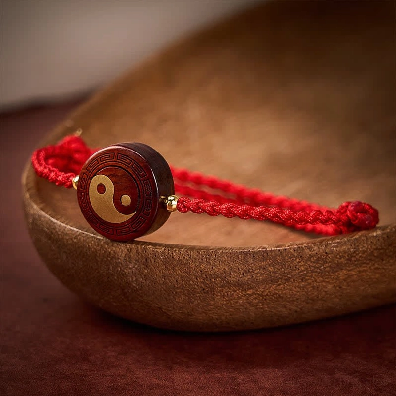 Purple sandalwood tai chi bracelet with protective red cord and gold spacers on wooden background