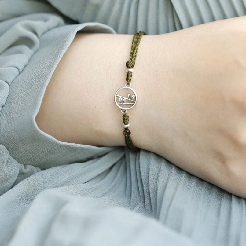 Side view of bamboo charm and bead arrangement on 925 silver red string bracelet worn casually
