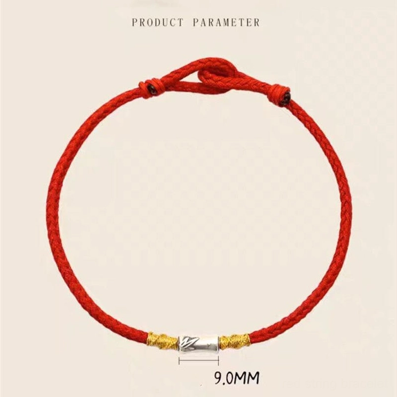 Bamboo silver charm placed next to red string on dark red background